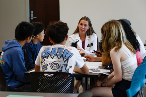 Student pharmacist Natalie Knepper speaks to a group of high school students at a table.