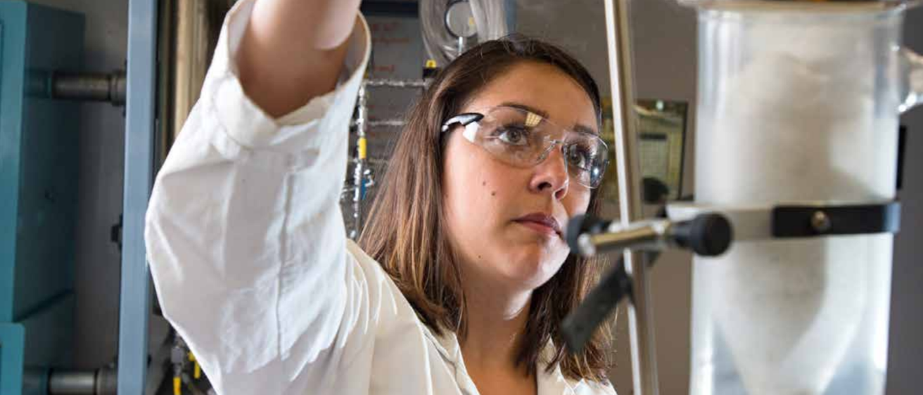 A researcher in lab coat and safety glasses.