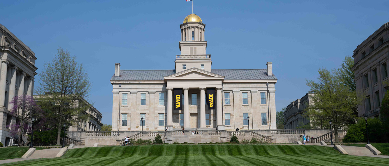 Old Capitol on a sunny day with Iowa banners hung for commencement