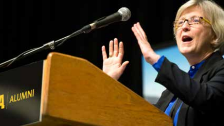 An Iowa alumna speaking at a podium.